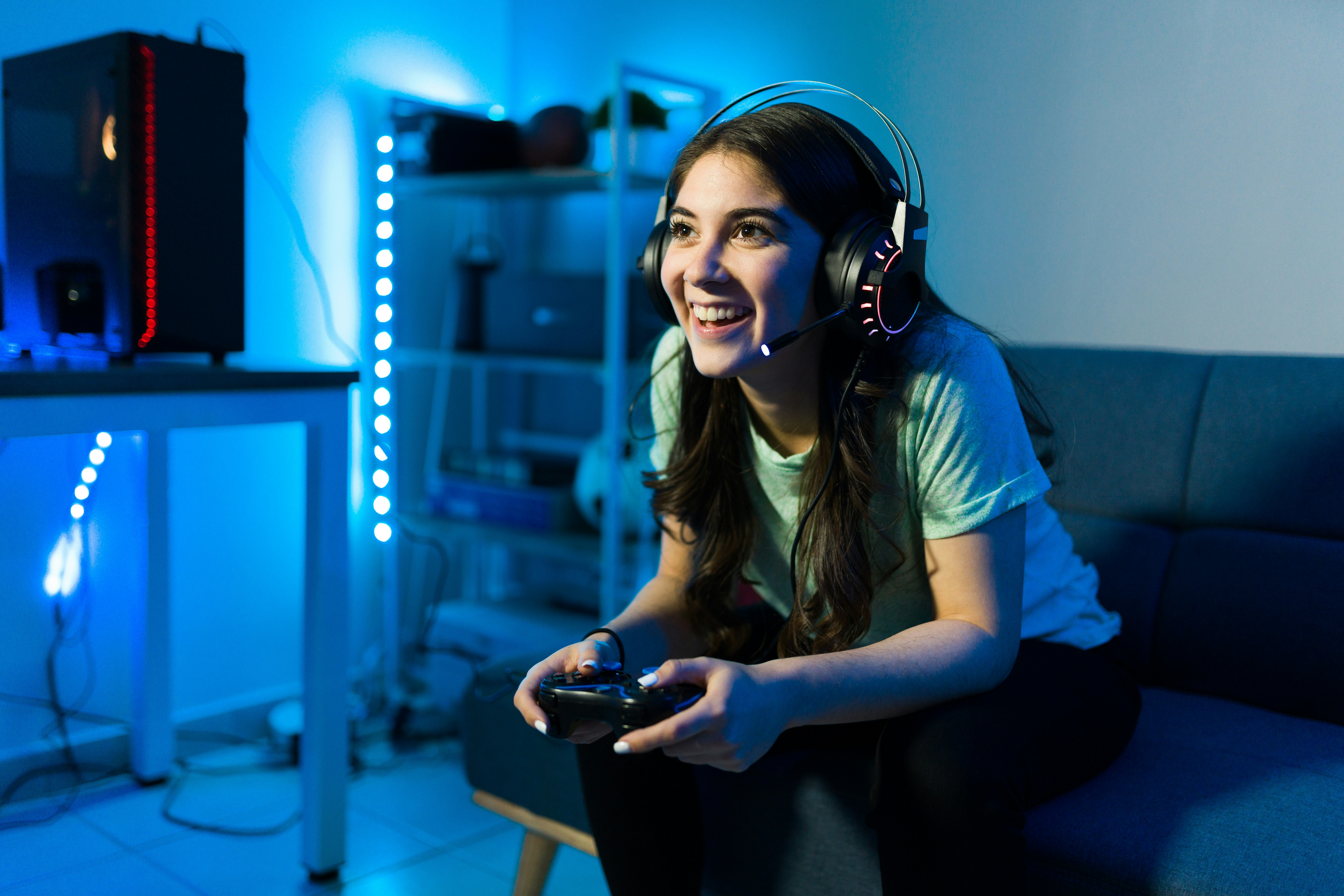 Female gamer playing video games wearing a headset in a neon lit room