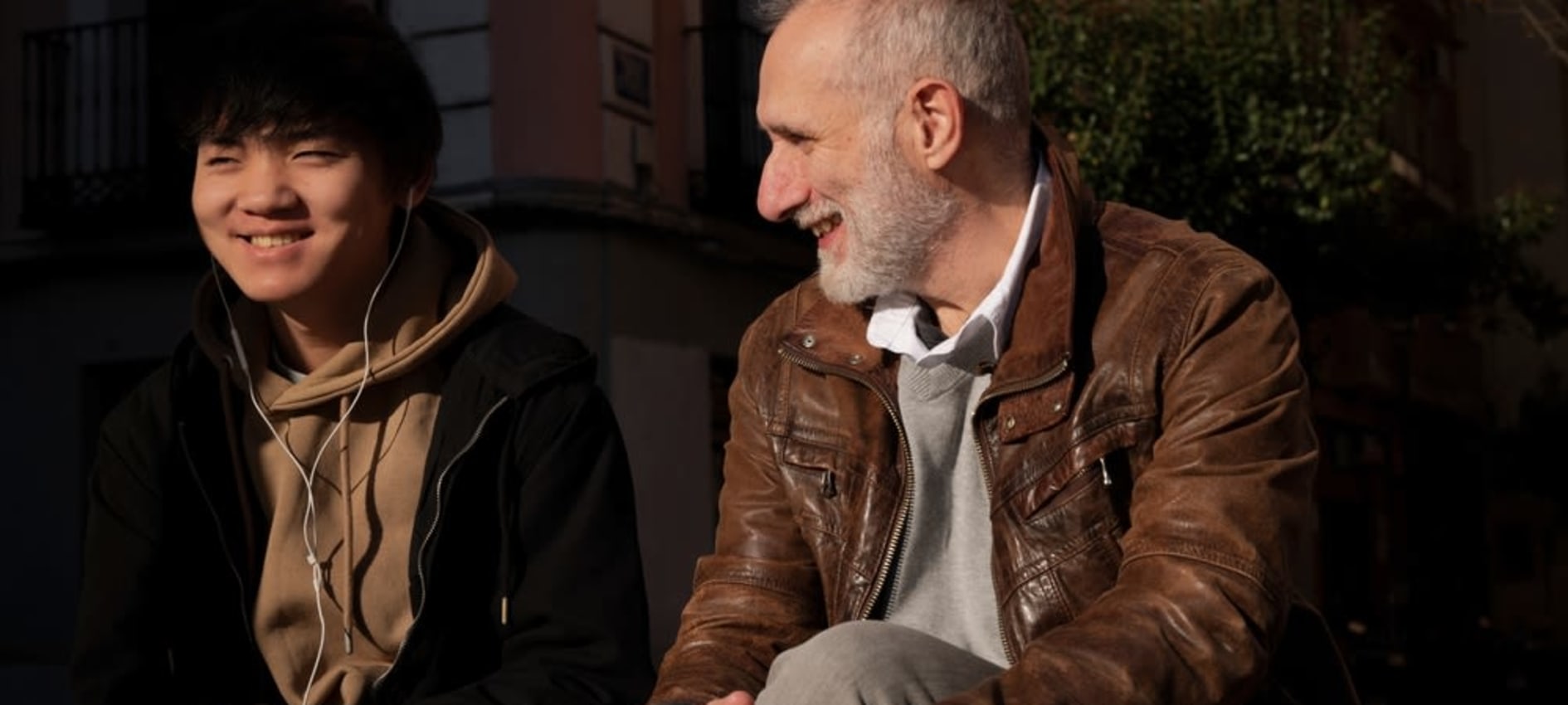 A social worker speaks with a young person on a park bench as they both smile