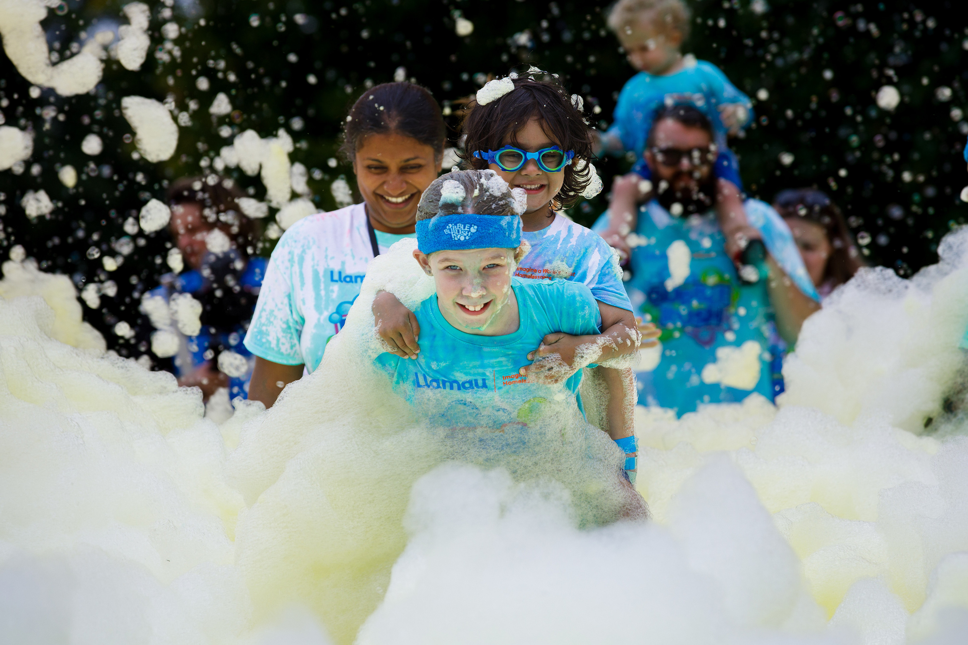 Two smiling children rushing into a wave of bubbles at a Bubble Rush event